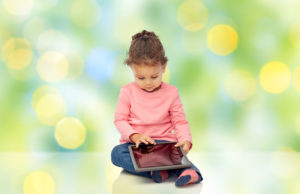 childhood, technology and people concept - little african american baby girl playing with tablet pc computer and sitting on floor